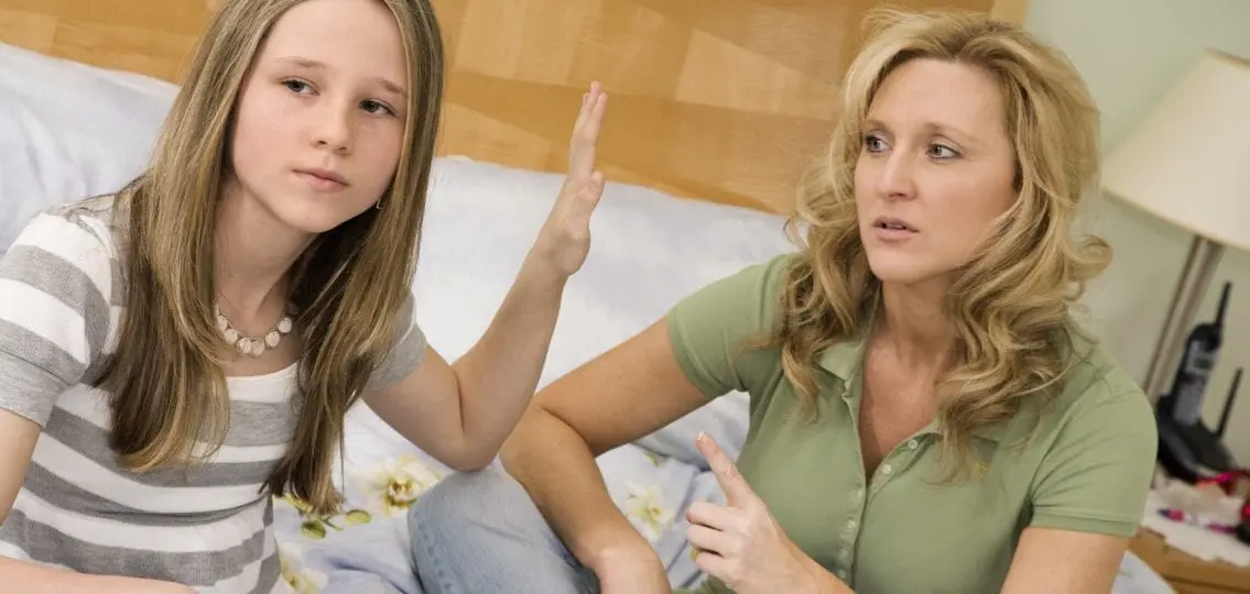 Teen daughter disrespecting mom holding hand in her face