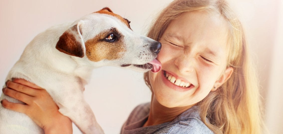 small Dog licking teen girl's face