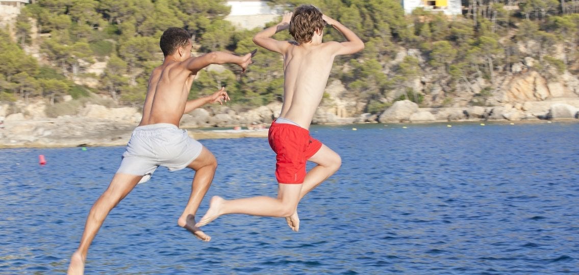 Boys jumping into a lake