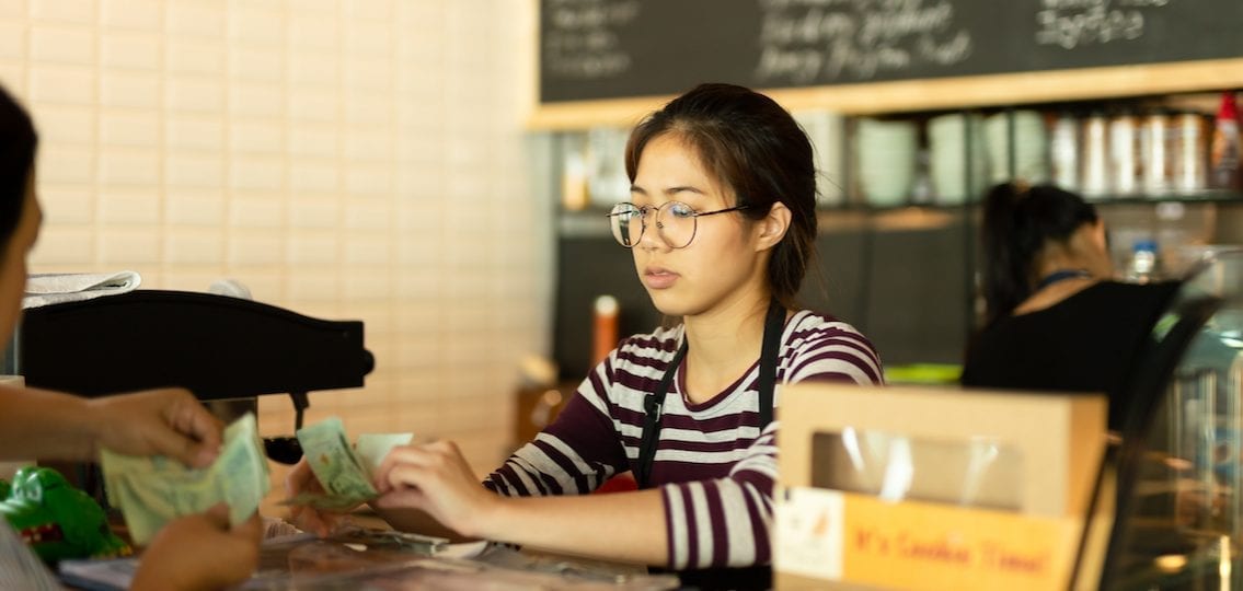 Teen girl working at a restaurant taking money