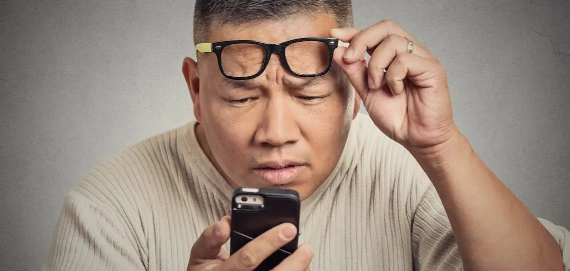 Closeup portrait headshot middle aged man with glasses having trouble seeing cell phone screen