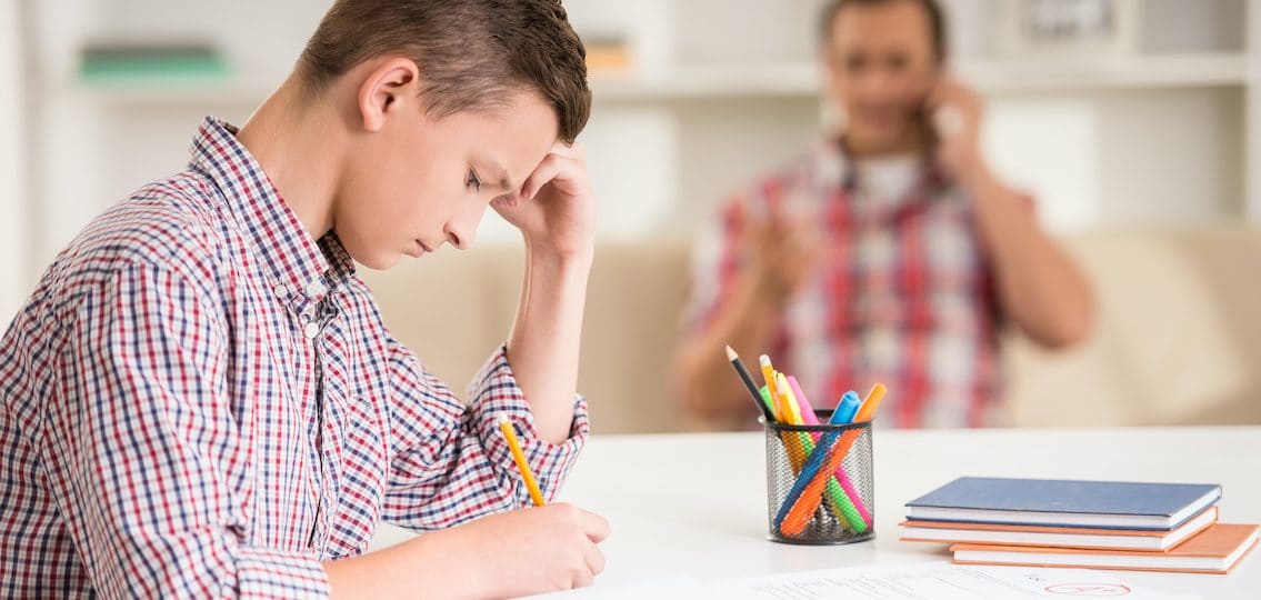 Father And Son At Home Middle schooler doing homework