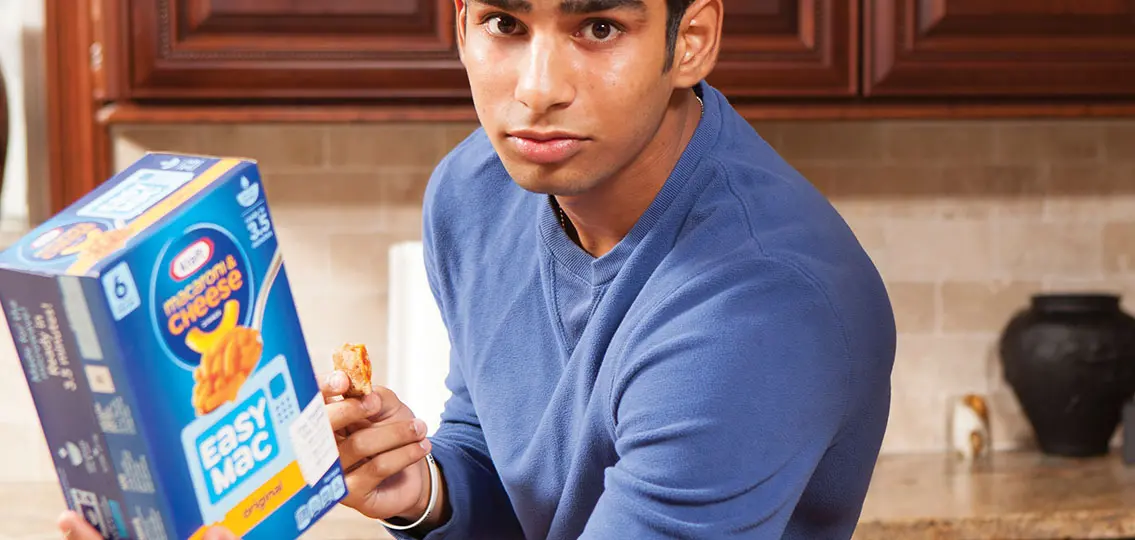 Boy Reading Nutrition Label on macaroni and cheese