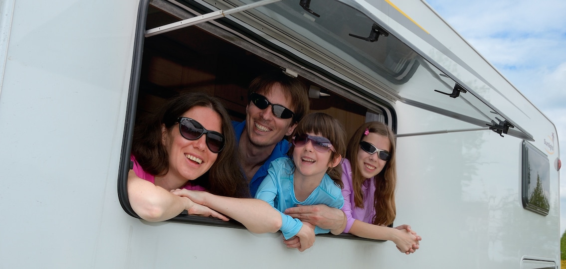 Family hanging out in an RV and smiling on a trip