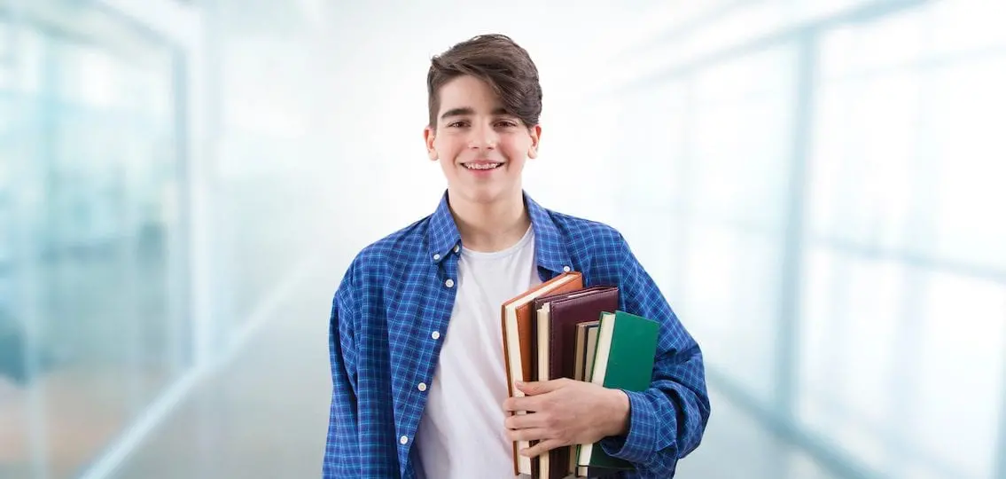 Teen boy holding school books in a blurry hallway