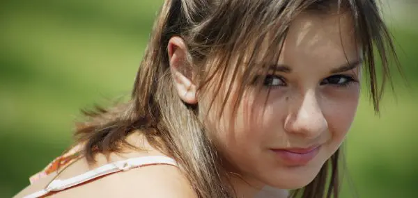 Teen girl looking into camera with a green background