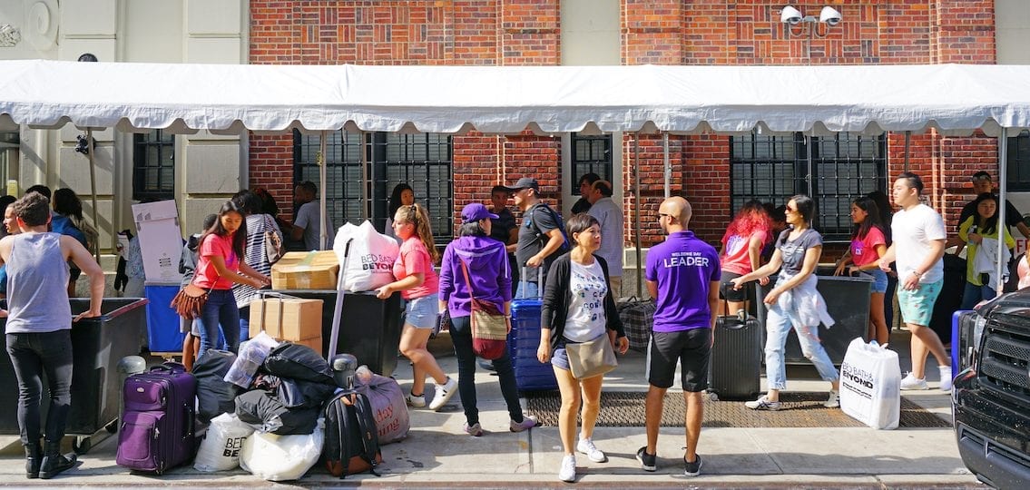 Move in day at college parents and teens unpacking outside dorm