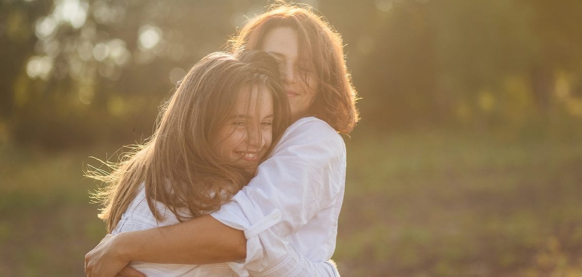Mom and daughter hugging outside in sunset spending time together