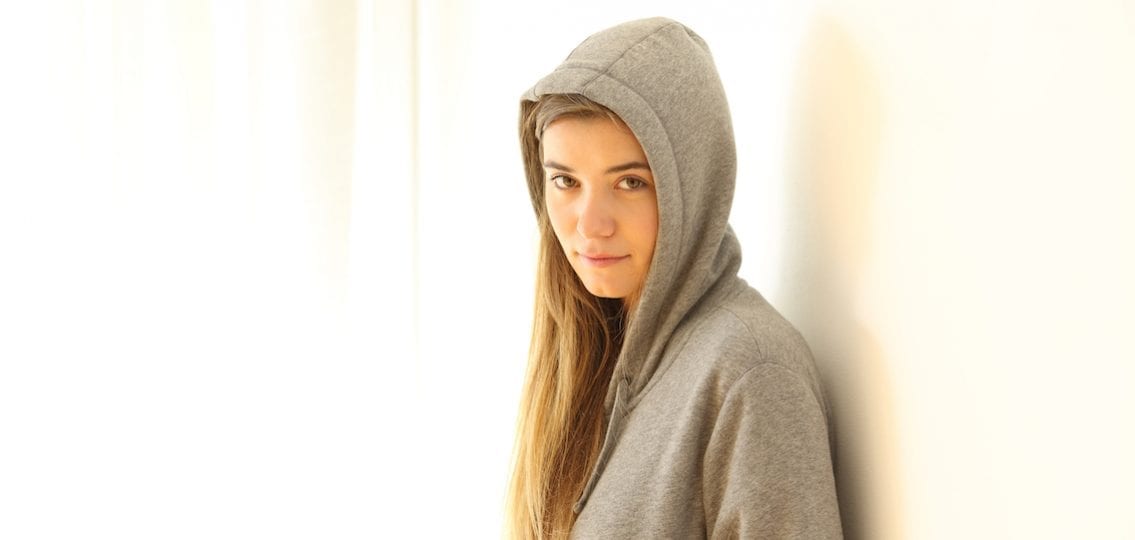 Teen stepdaughter in hoodie leaning against a wall