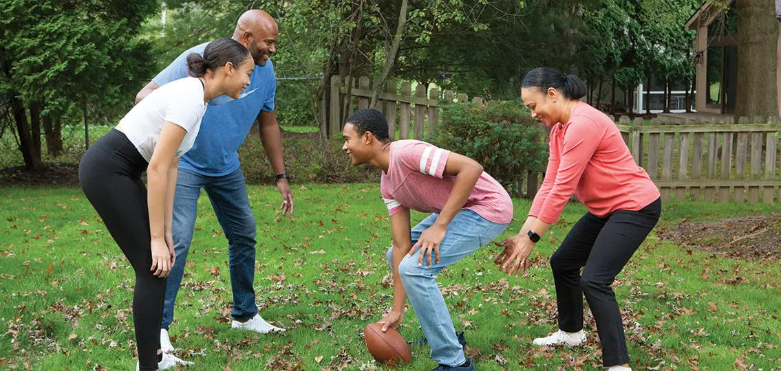 Family playing football outside in backyard