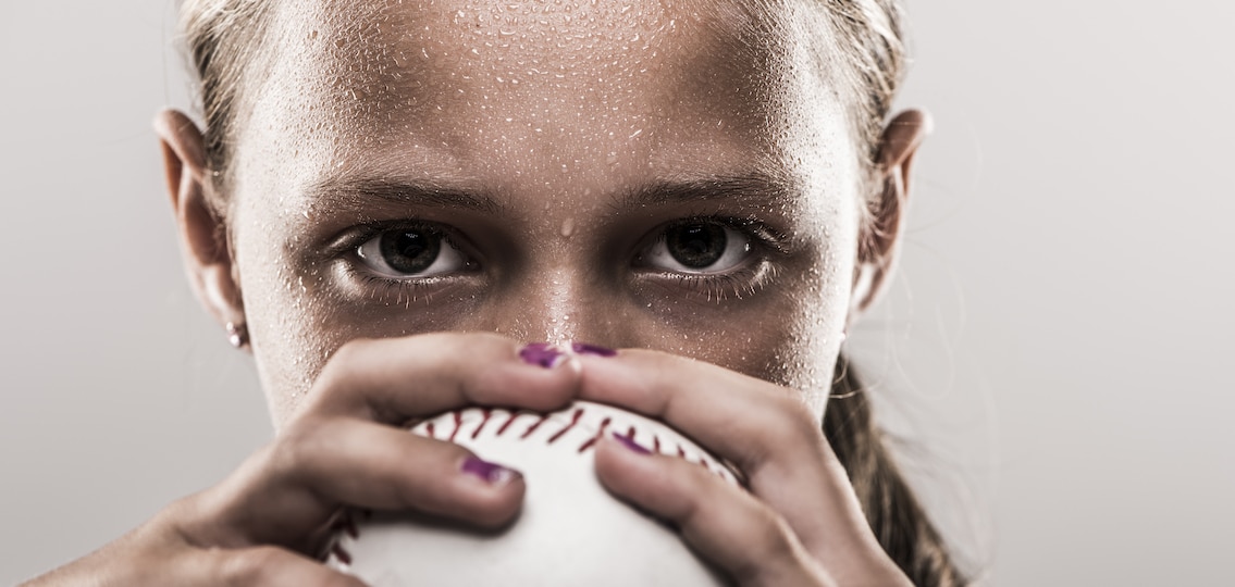perfectionist Teen girl playing baseball close up serious face