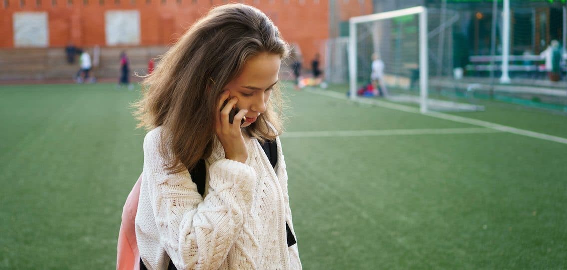 Teen on phone at soccer field