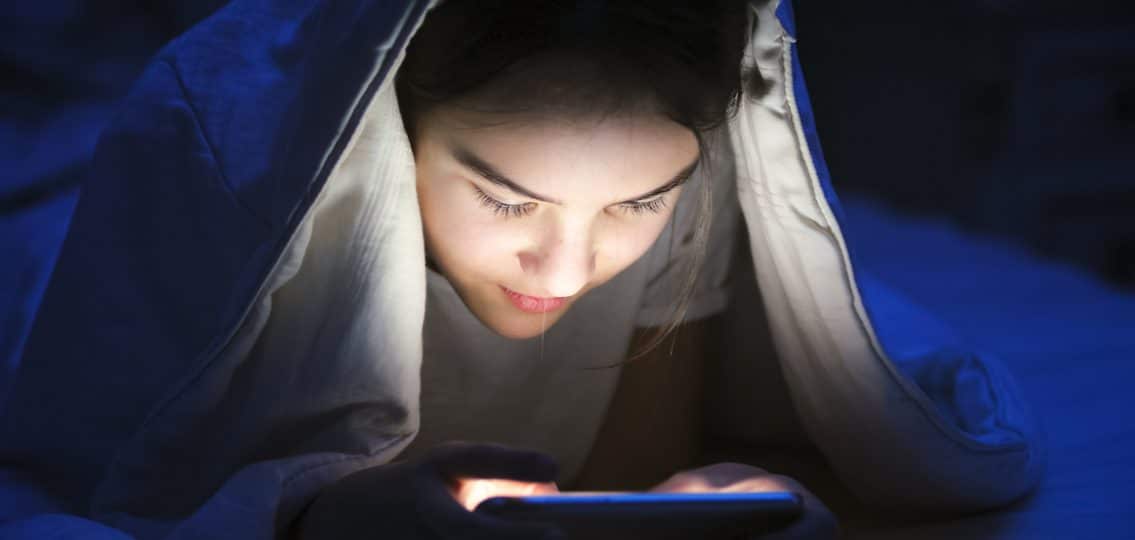 Girl on phone under covers
