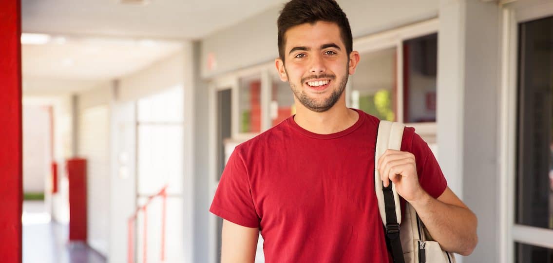 Young man at college in dormroom hallway