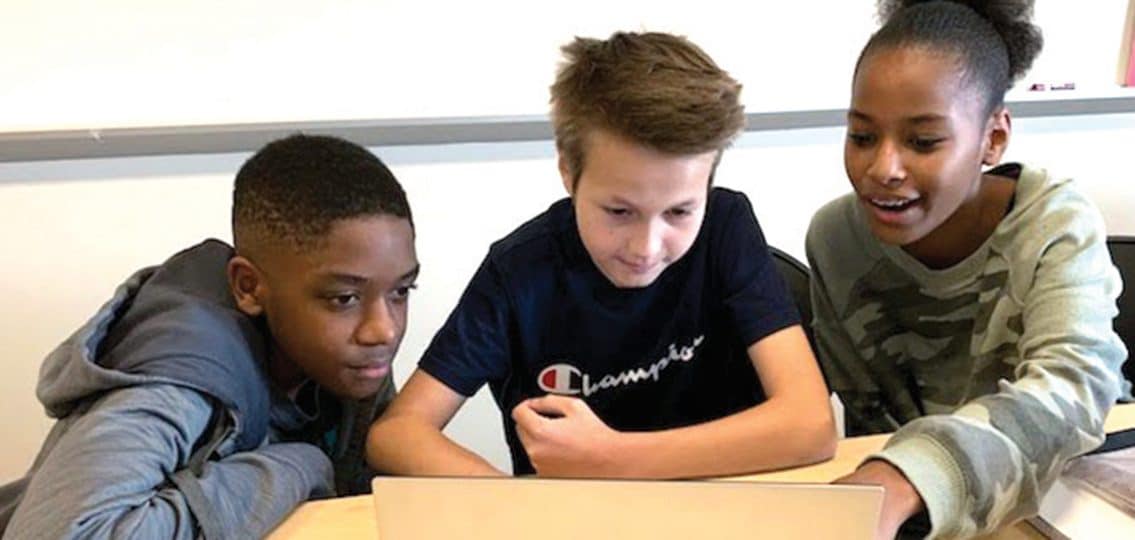 three middle schoolers working on a computer