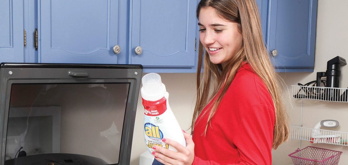 teen doing laundry looking at laundry detergent