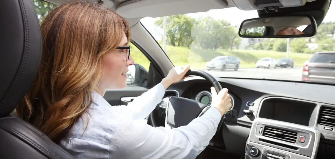 Driving woman in carpool looking into rearview mirror