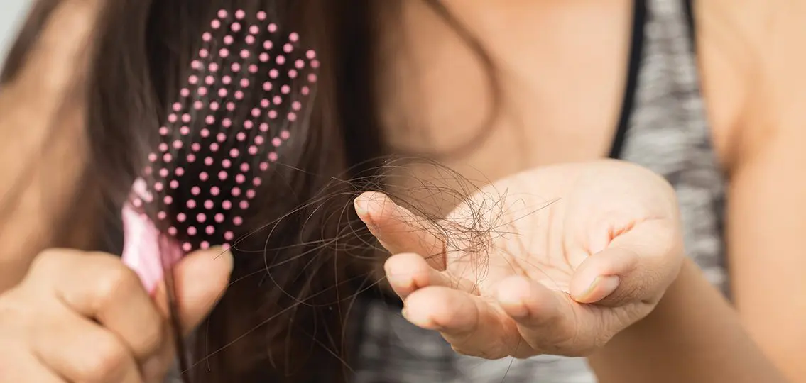 teenage girl holding clump of hair worried about hair loss