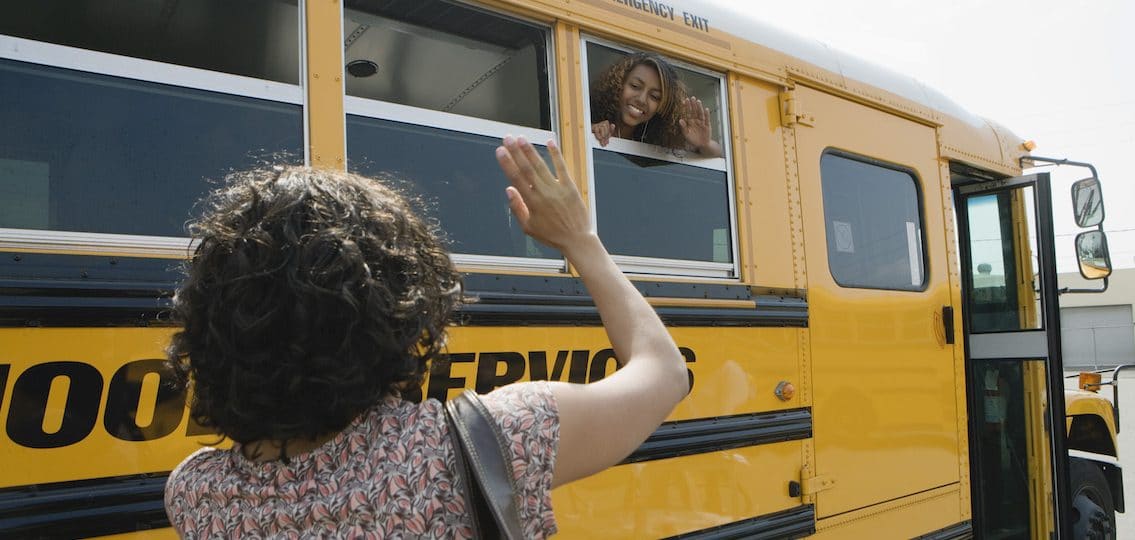 Mother Waving to Teenage Daughter in School Bus