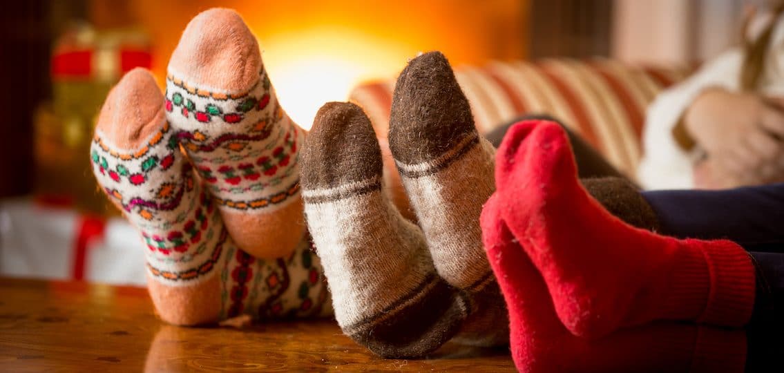 Closeup photo of family feet in wool socks at fireplace holiday themed