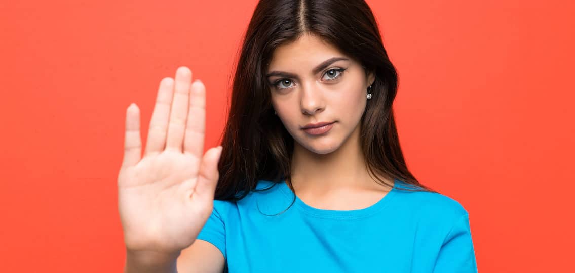 Teenager girl with blue shirt making stop gesture with her hand