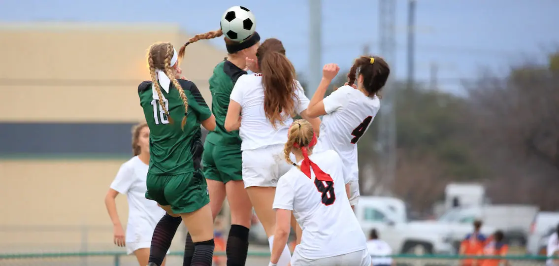 teen girl soccer players heading a ball