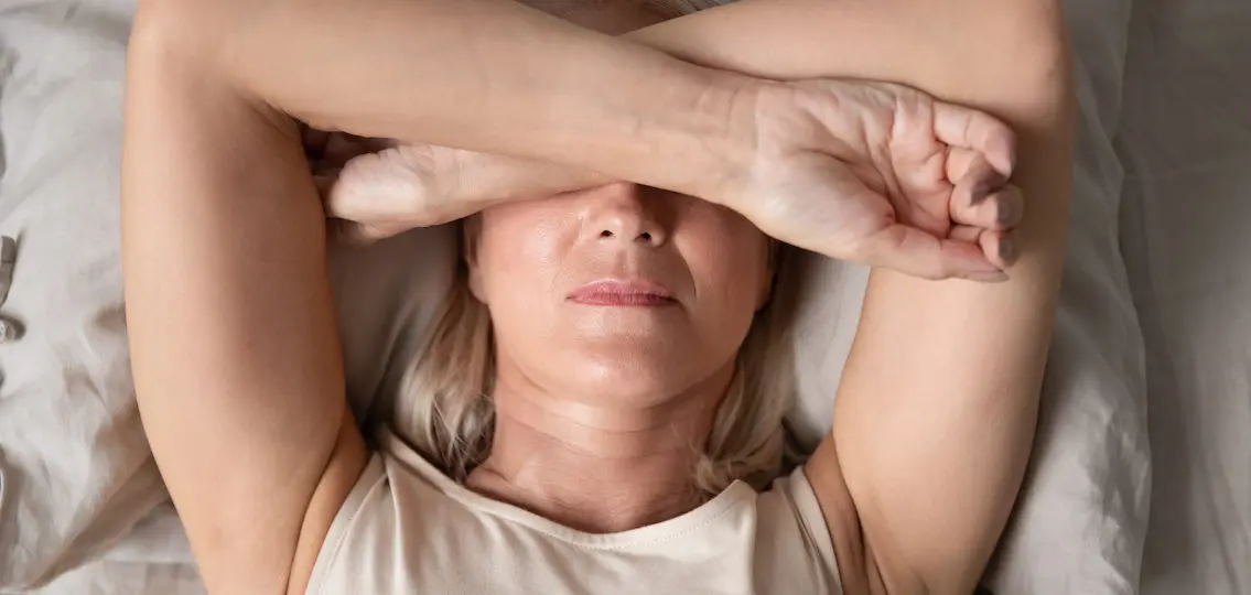 anxious mom lying in bed covering her face