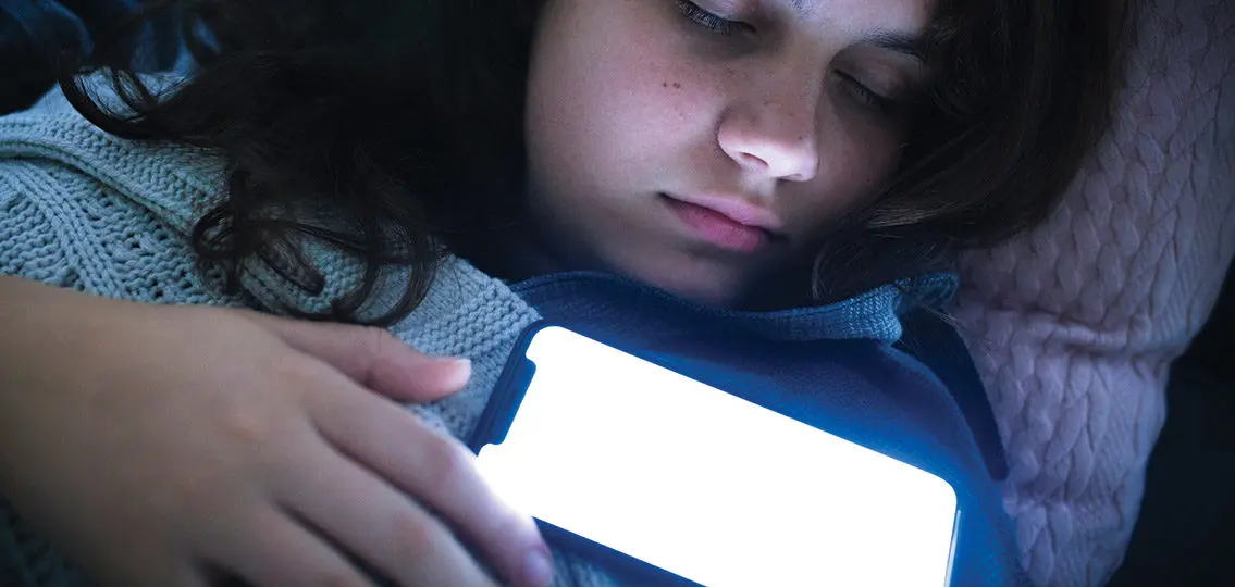 teen Girl Fast Asleep With Her Phone glowing On Her Chest