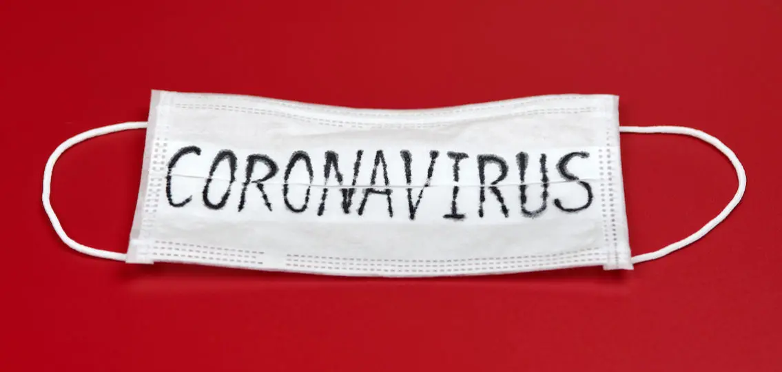 face mask with coronavirus written in pen on a red background