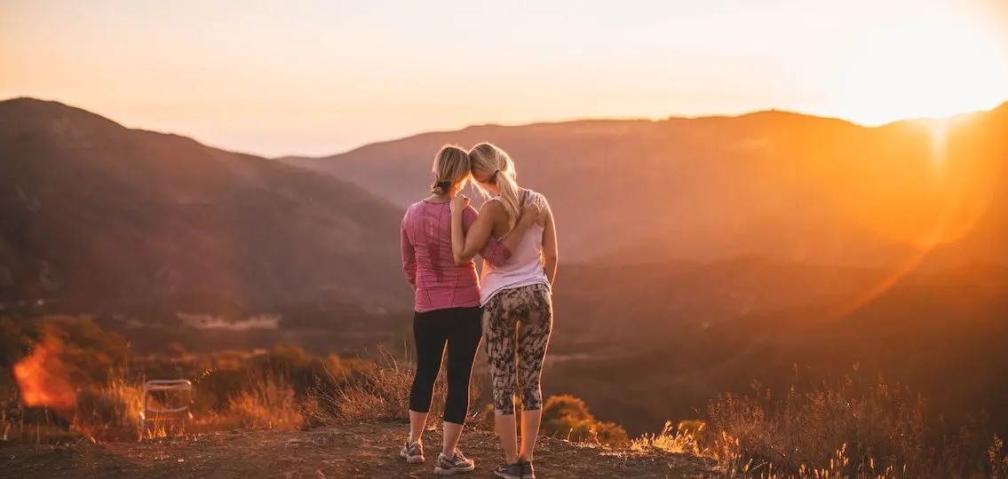 mom and daughter on a hike watching the sunset