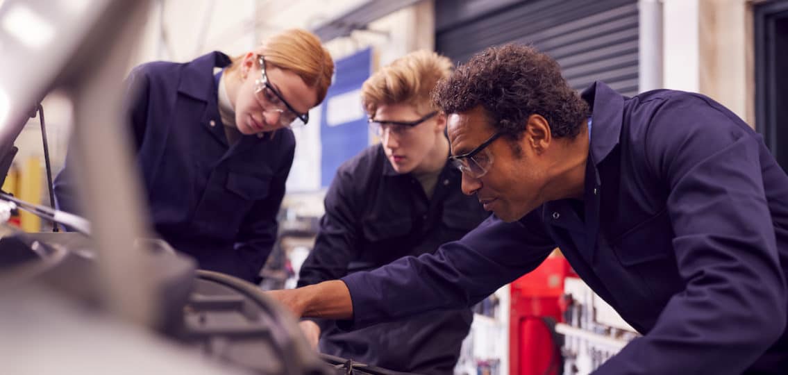 teens and an engineer working in an auto shop together