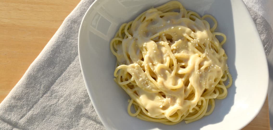 bechamel on spaghetti in a white bowl