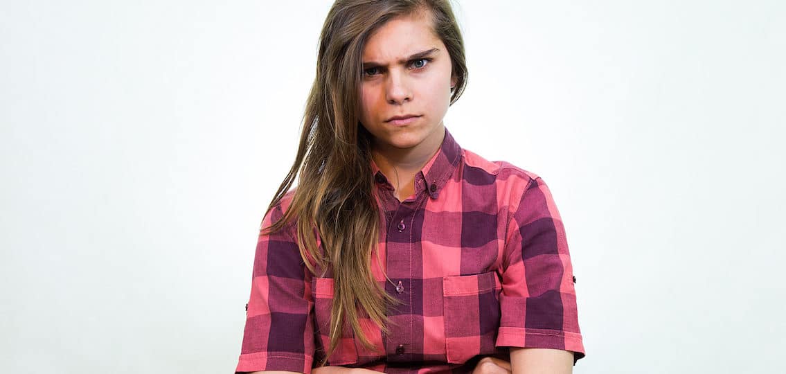 Angry teenager girl is looking into the camera with a piercing gaze.