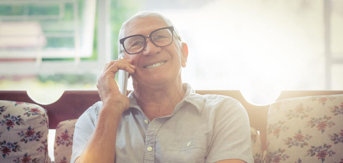 Senior man talking on mobile phone at home and smiling