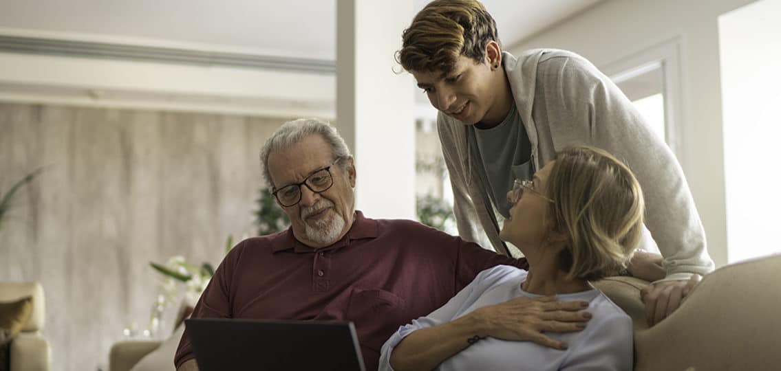 Teenager Boy Using Notebook With Grandparents