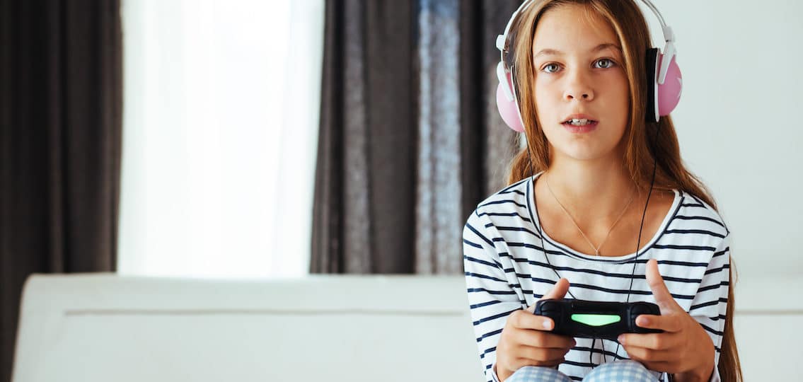 young teenage girl playing a video game with headphones on