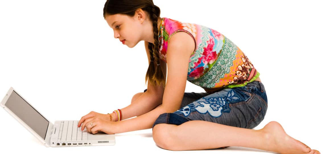 teenage girl using a laptop and smiling isolated over white