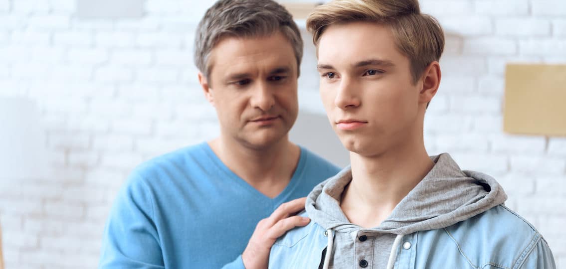 Father tries to talk to his teen son, but problem teenager doesn't want to listen. Father reaches out with his hand.