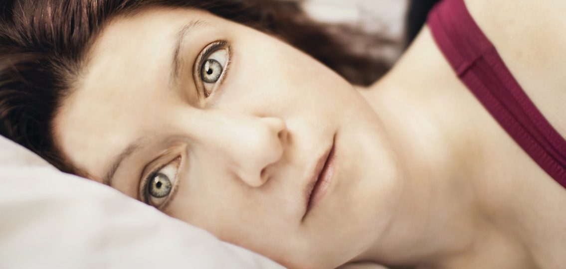 frightened single mom lying awake in bed staring at the camera