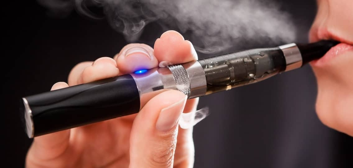 Close up of a woman inhaling from an electronic cigarette