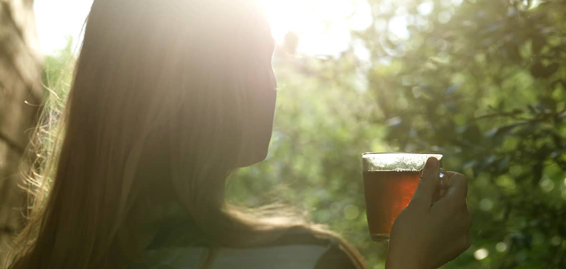 Woman With Cup Of Tea In Evening Sunlight outdoors