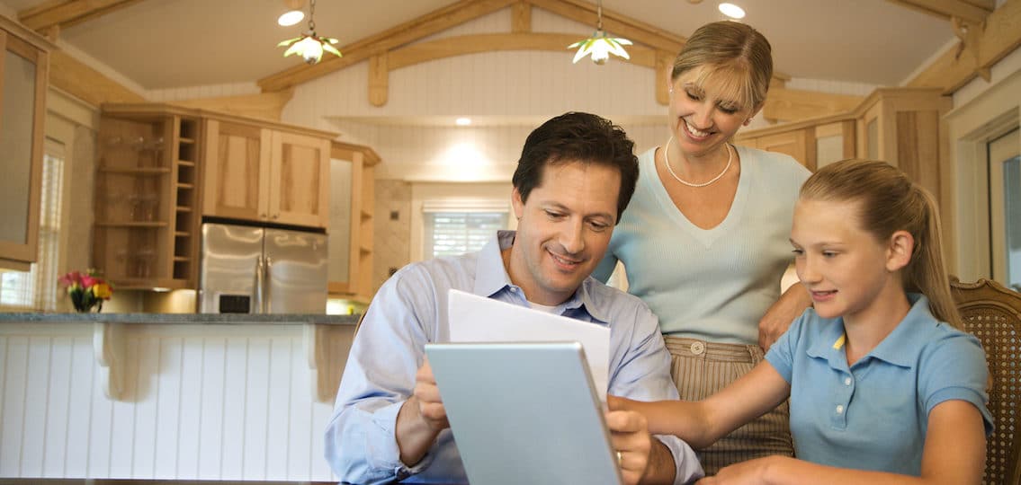 family looking at bills together in the kitchen at a computer