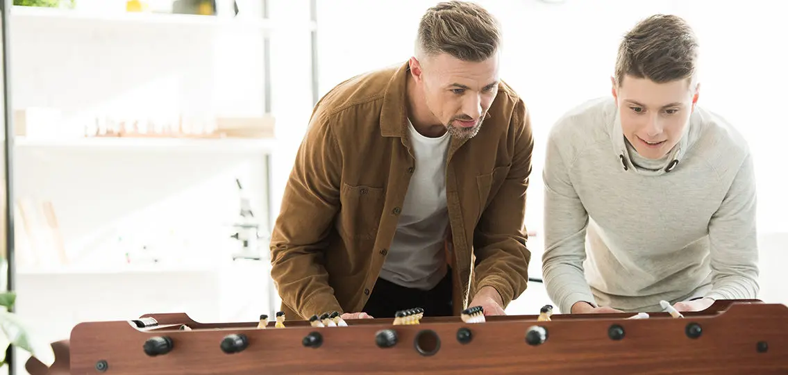 Dad and son playing a foosball table together