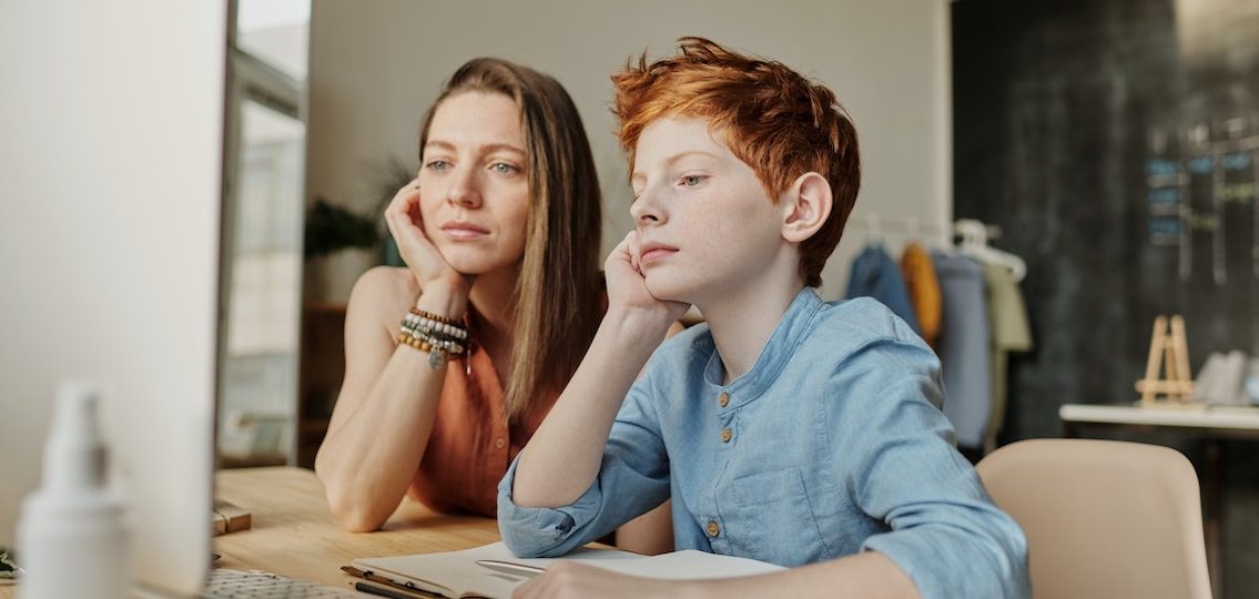 frustrated teen boy and mom looking at computer and homework together