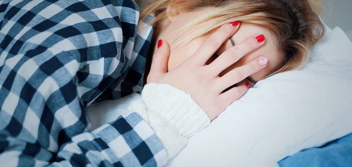 Young woman crying in bed covering her face sad