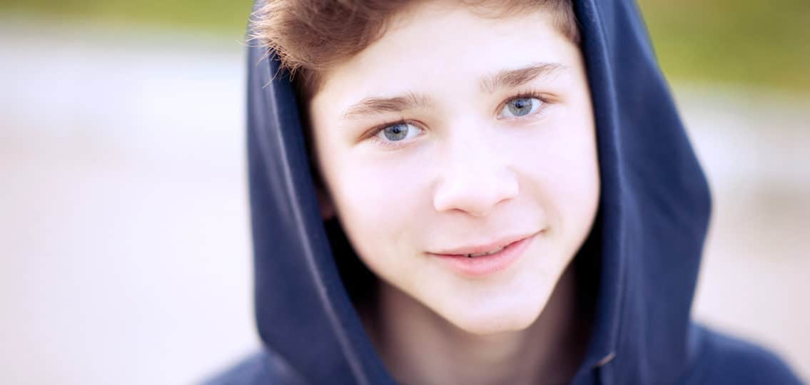 young teen boy in a hoodie smiling close up