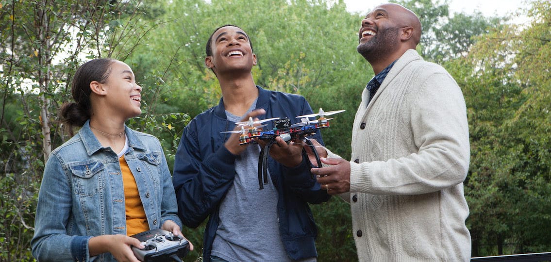 Dad And Teens Laughing With Drone in backyard
