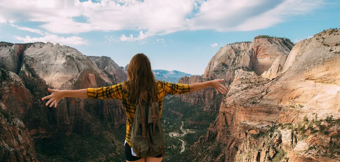 teen girl at top of a mountain arms open