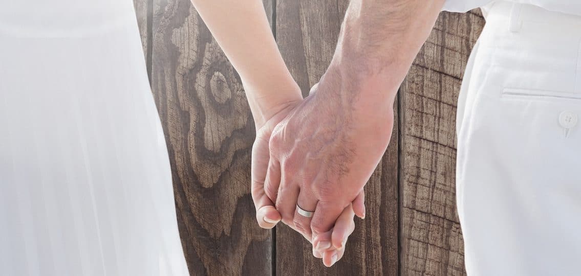 Digital composite of Wedding couple holding hands against wood