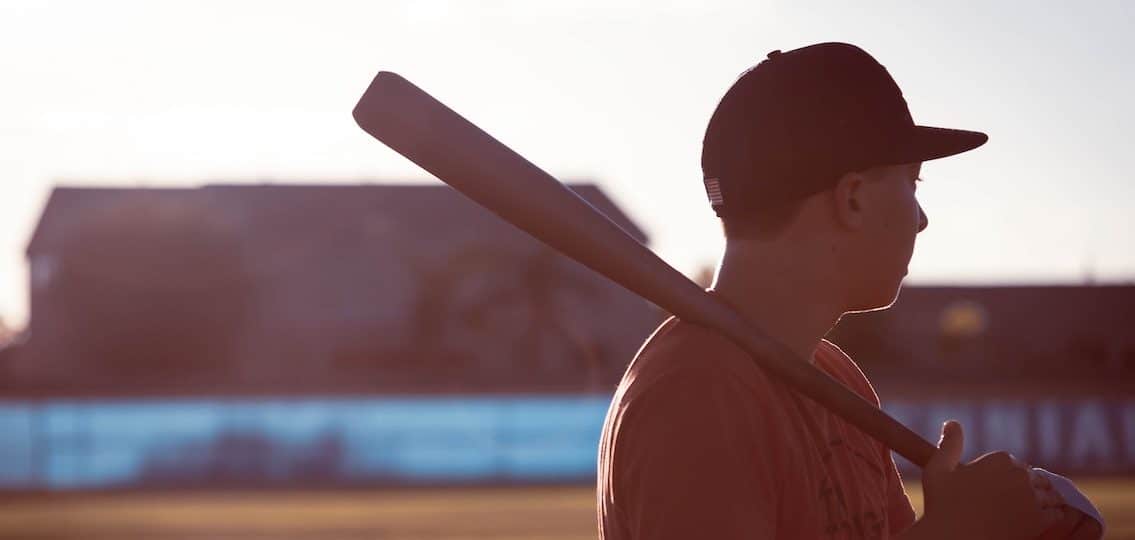 Teen boy on empty field with baseball bat blurred background